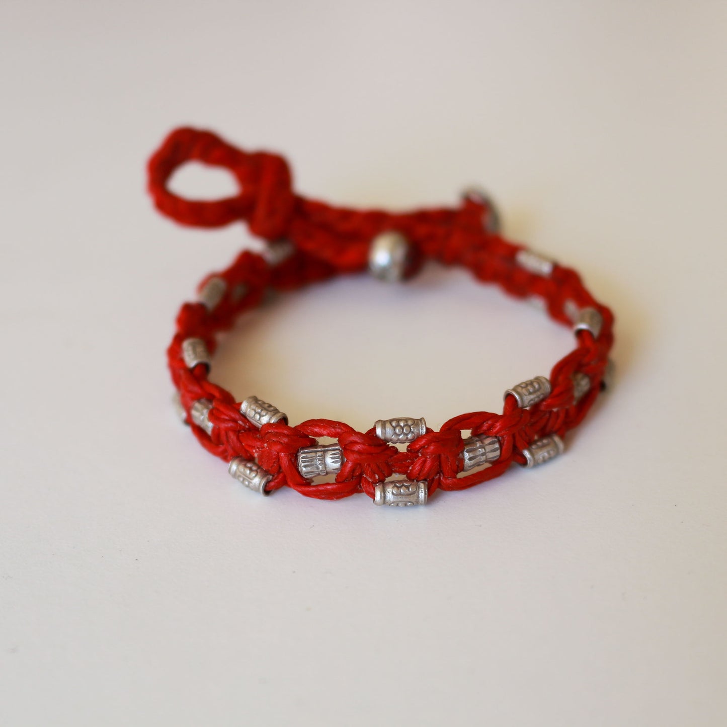 Silver beads on red cord bracelet